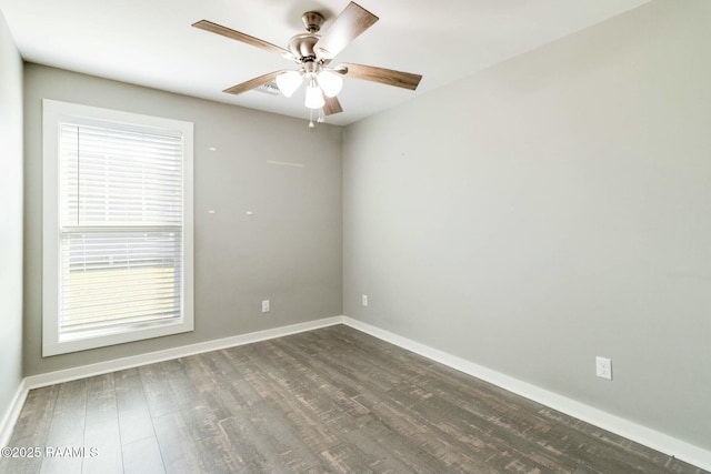 spare room with dark wood finished floors, a ceiling fan, and baseboards