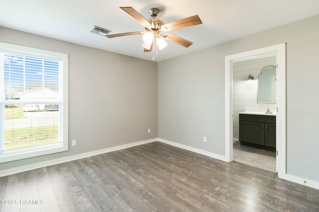 unfurnished bedroom with ceiling fan, connected bathroom, wood finished floors, visible vents, and baseboards