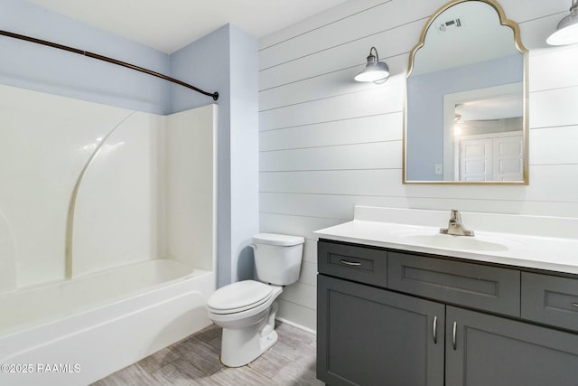 full bath with shower / bathtub combination, visible vents, toilet, vanity, and wood finished floors