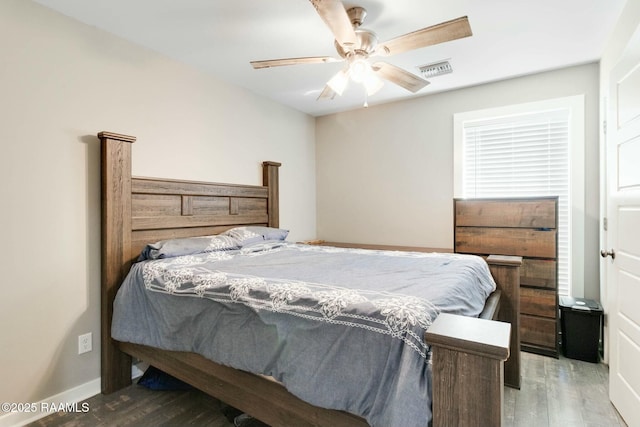 bedroom with ceiling fan, wood finished floors, visible vents, and baseboards