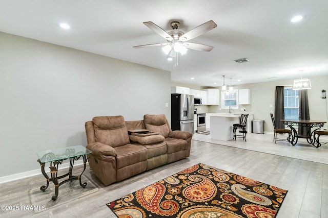 living room with light wood finished floors, visible vents, baseboards, ceiling fan, and recessed lighting