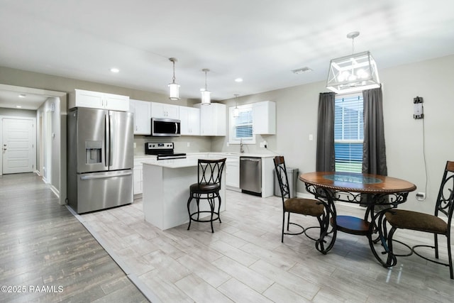 kitchen with light countertops, appliances with stainless steel finishes, white cabinets, and a center island