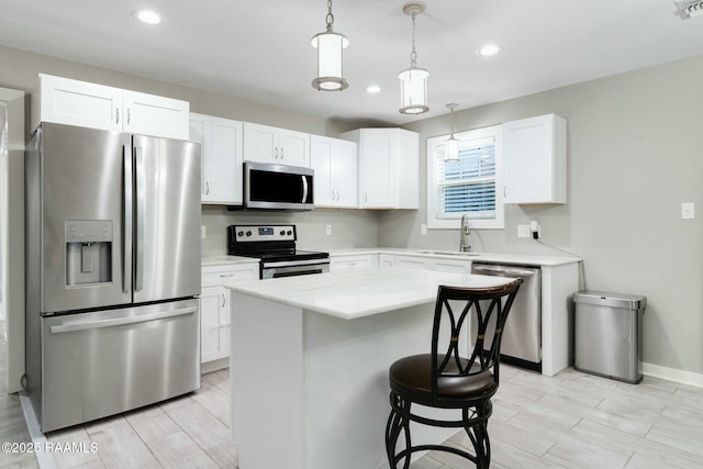 kitchen featuring appliances with stainless steel finishes, a breakfast bar, light countertops, white cabinetry, and a sink