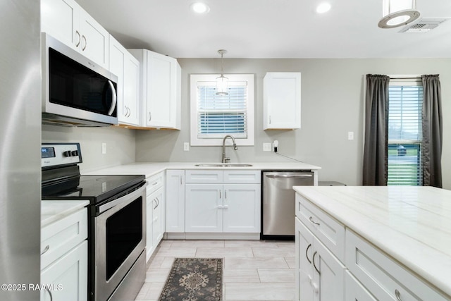 kitchen with stainless steel appliances, light countertops, visible vents, white cabinets, and a sink