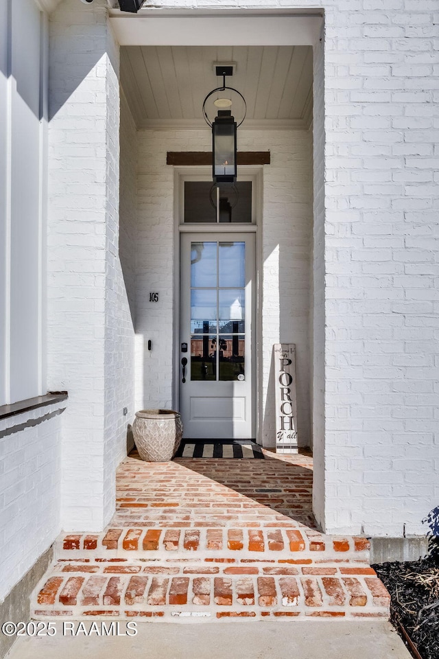 doorway to property featuring covered porch and brick siding