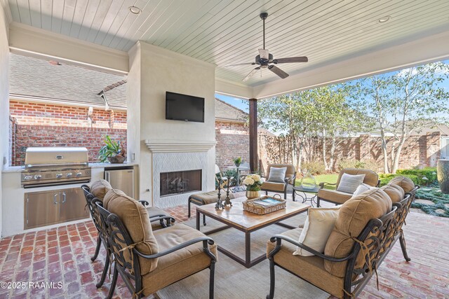 view of patio / terrace featuring an outdoor living space with a fireplace, area for grilling, fence, and a ceiling fan