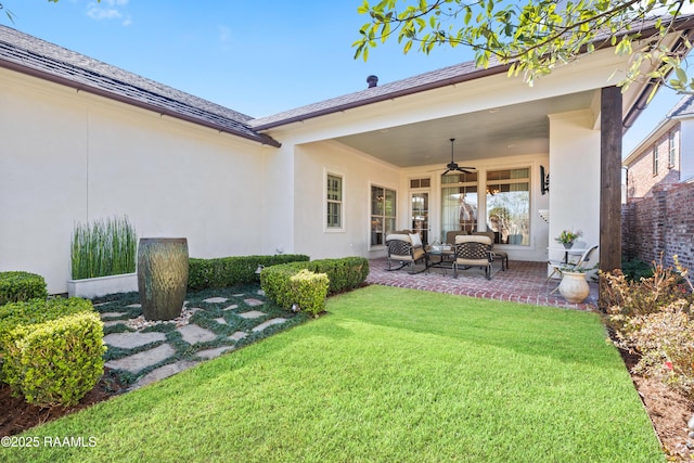 rear view of property featuring a patio, stucco siding, a lawn, an outdoor hangout area, and ceiling fan