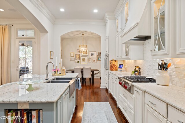 kitchen featuring dark wood-style floors, ornamental molding, premium range hood, stainless steel gas stovetop, and white cabinetry