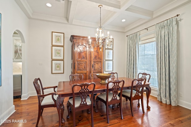 dining room with baseboards, beam ceiling, arched walkways, and wood finished floors