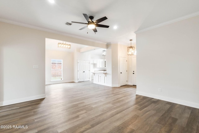 unfurnished living room featuring baseboards, ceiling fan with notable chandelier, wood finished floors, and crown molding