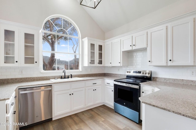 kitchen featuring lofted ceiling, light wood-style flooring, a sink, white cabinetry, and appliances with stainless steel finishes