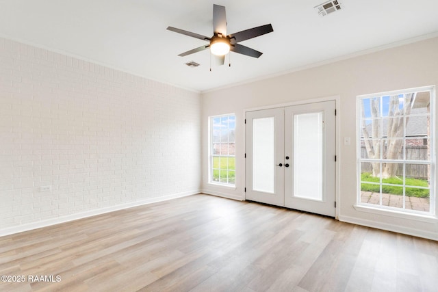 empty room featuring visible vents, crown molding, brick wall, and wood finished floors