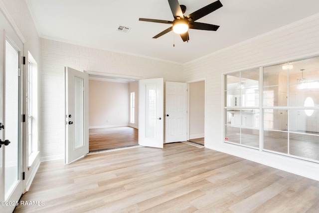 spare room with plenty of natural light, ornamental molding, light wood-type flooring, and visible vents