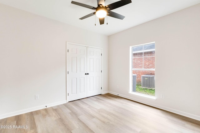 unfurnished bedroom with multiple windows, light wood-type flooring, a closet, and baseboards