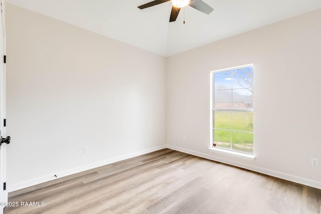 empty room featuring a ceiling fan, baseboards, vaulted ceiling, and wood finished floors