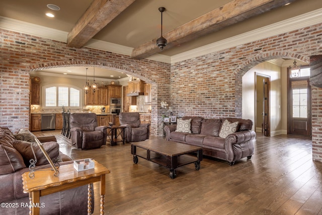 living area featuring arched walkways, beam ceiling, brick wall, and hardwood / wood-style flooring