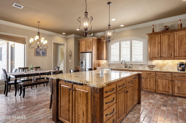 kitchen with brick floor, a sink, visible vents, decorative backsplash, and stainless steel fridge