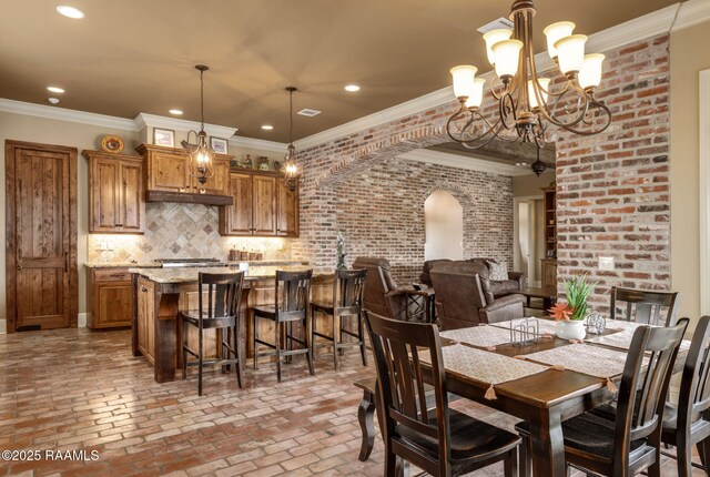 dining area with brick floor, arched walkways, ornamental molding, and recessed lighting