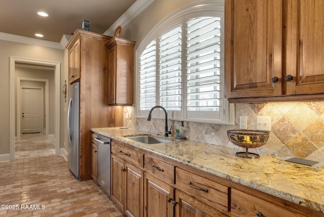 kitchen featuring crown molding, tasteful backsplash, appliances with stainless steel finishes, brown cabinetry, and a sink