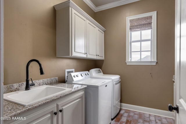 washroom featuring a sink, baseboards, cabinet space, washer and clothes dryer, and crown molding