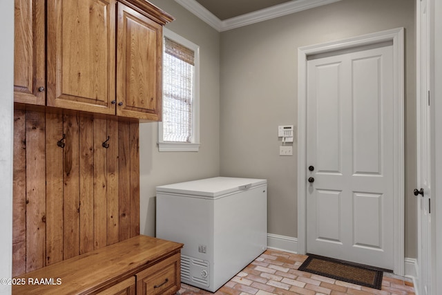 laundry area with brick floor, cabinet space, crown molding, and baseboards