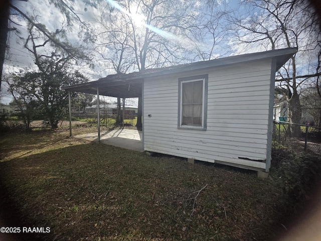 view of side of property with a patio, a carport, an outdoor structure, and fence