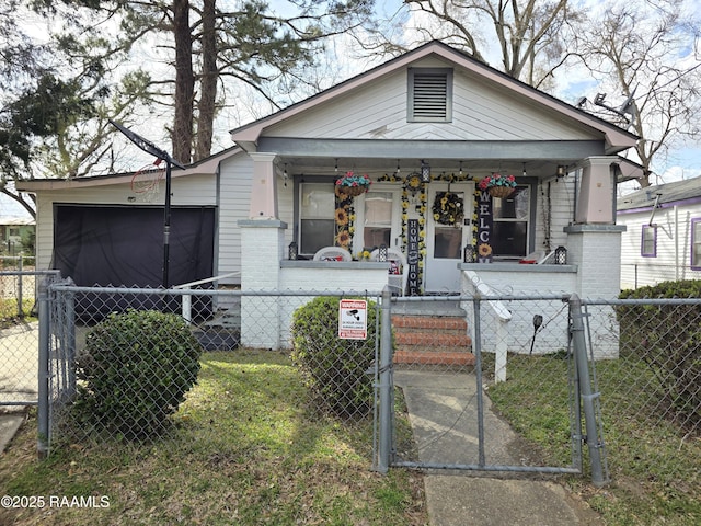 view of front of home with a porch, a gate, brick siding, and a fenced front yard