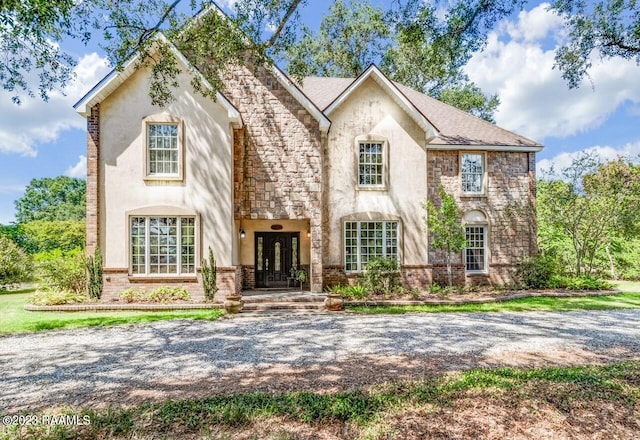 french country home featuring stone siding and brick siding