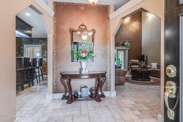 foyer featuring arched walkways, stone finish flooring, and baseboards