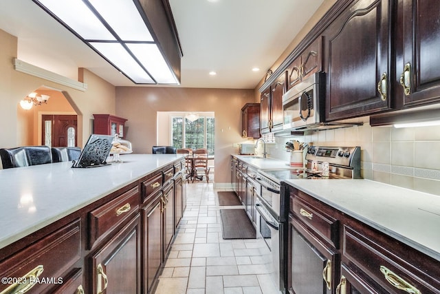 kitchen with arched walkways, light countertops, appliances with stainless steel finishes, and tasteful backsplash