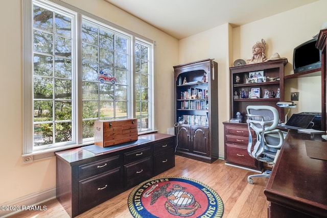 office area with a healthy amount of sunlight, light wood-style floors, and baseboards