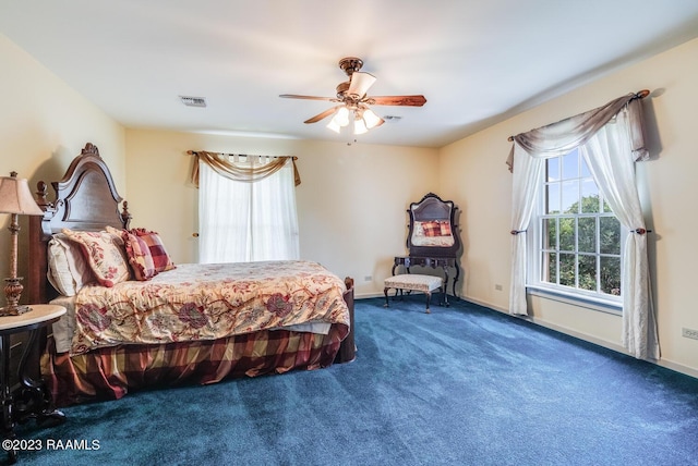 carpeted bedroom with ceiling fan, multiple windows, visible vents, and baseboards