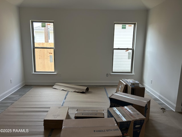 spare room with baseboards and wood finished floors