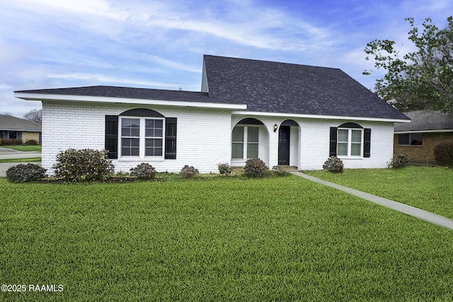 view of front of property featuring brick siding, roof with shingles, and a front yard