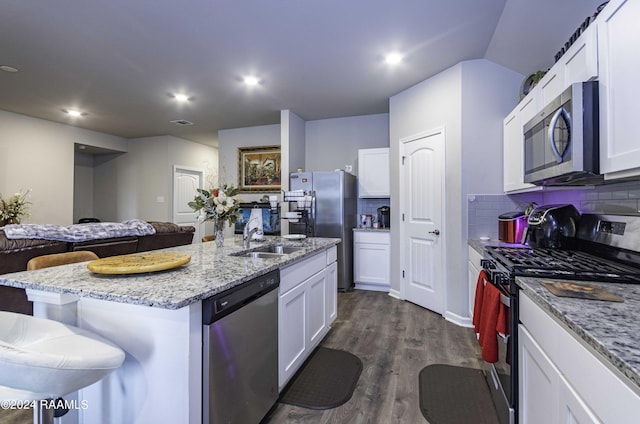 kitchen featuring backsplash, dark wood-type flooring, appliances with stainless steel finishes, white cabinets, and a kitchen island with sink