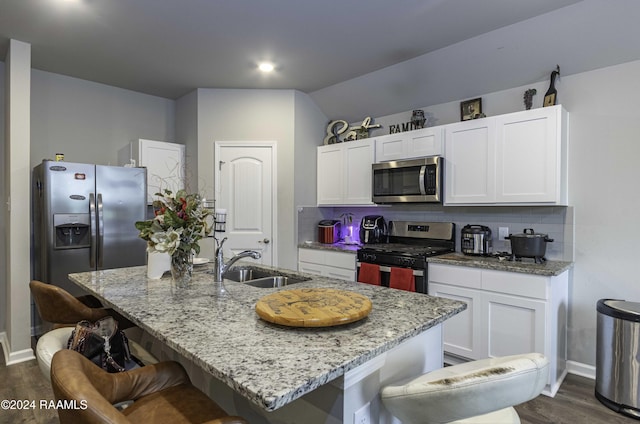 kitchen with a sink, decorative backsplash, dark wood-type flooring, appliances with stainless steel finishes, and white cabinetry