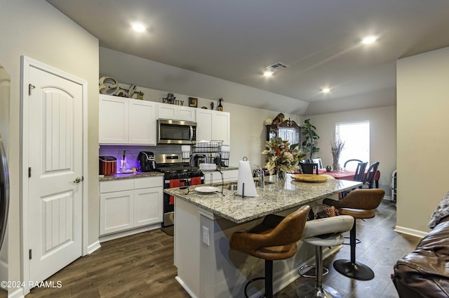 kitchen featuring visible vents, appliances with stainless steel finishes, a kitchen breakfast bar, white cabinetry, and a sink