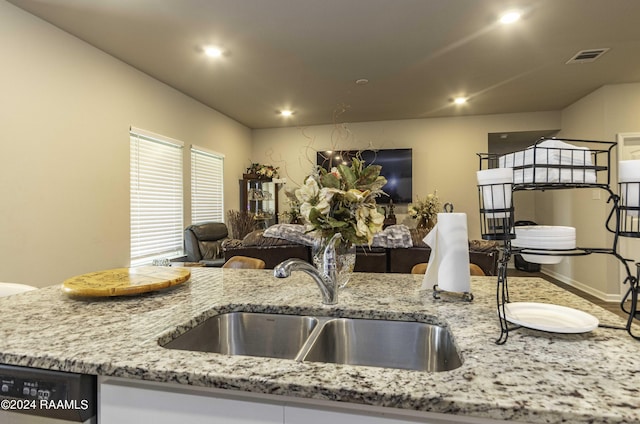 kitchen with a sink, light stone counters, open floor plan, recessed lighting, and dishwashing machine