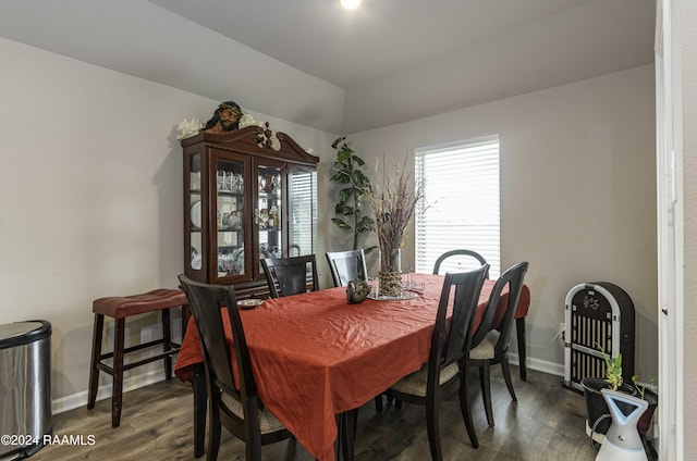 dining space featuring baseboards, wood finished floors, and vaulted ceiling