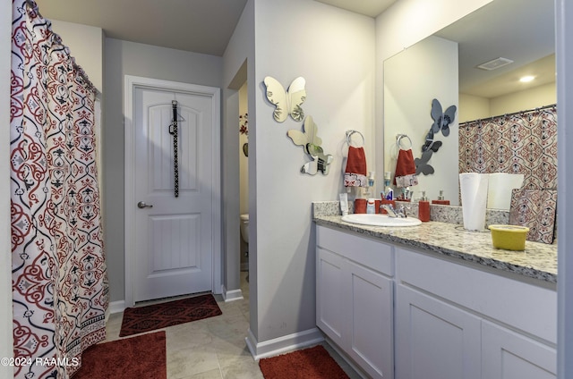 bathroom featuring tile patterned flooring, visible vents, baseboards, toilet, and vanity