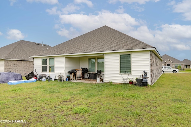 back of property featuring a lawn and roof with shingles