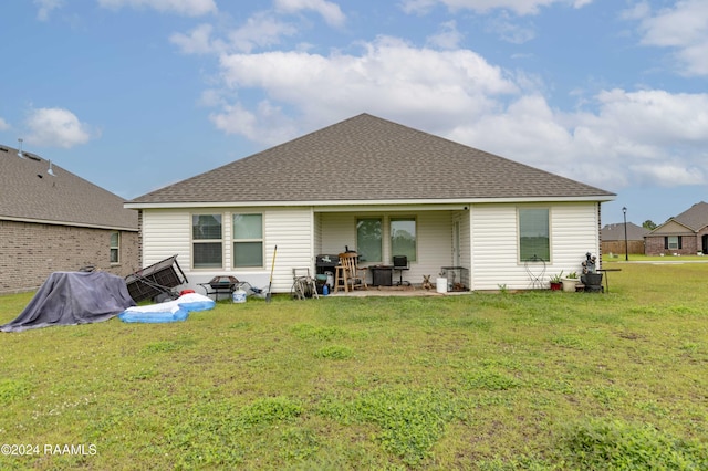 rear view of property with a patio, a lawn, and a shingled roof