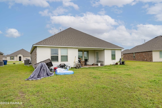 back of property featuring a patio area, cooling unit, a yard, and roof with shingles