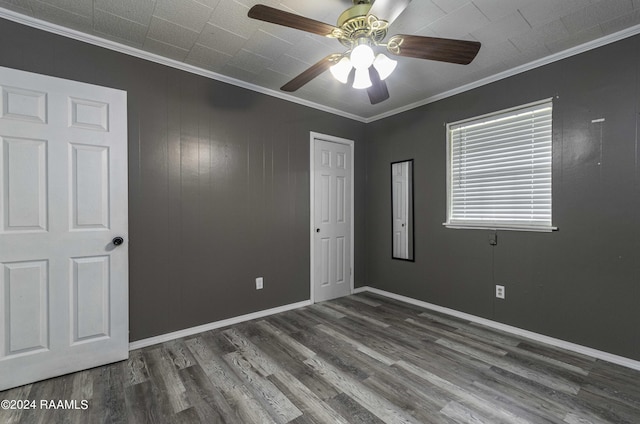 unfurnished bedroom with wood finished floors, baseboards, ceiling fan, ornamental molding, and a closet