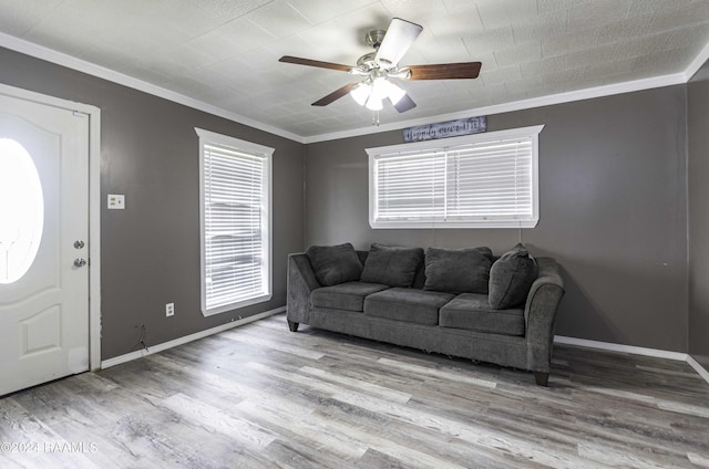 living area with a ceiling fan, crown molding, baseboards, and wood finished floors