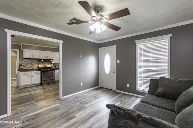 foyer with a ceiling fan, crown molding, wood finished floors, and baseboards