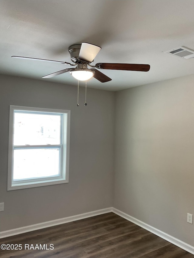 spare room featuring dark wood-style floors, visible vents, ceiling fan, and baseboards