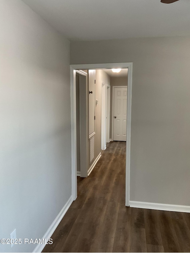 corridor featuring baseboards and dark wood finished floors