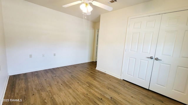 unfurnished bedroom featuring a closet, visible vents, a ceiling fan, wood finished floors, and baseboards