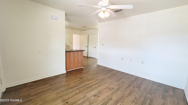 unfurnished room featuring visible vents, wood finished floors, a ceiling fan, and baseboards